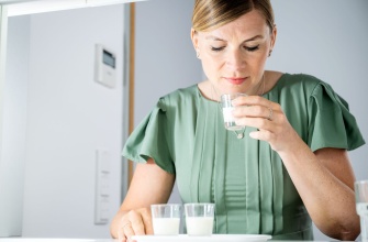 Eine Frau in einem grünen Kleid riecht an einer Aromenprobe, eine milchige Flüssigkeit in einem kleinen Shotglas. Vor ihr stehen 2 weitere Proben zum nächsten Vergleich.