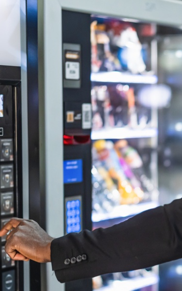 man in front of a vending machine selecting a drink