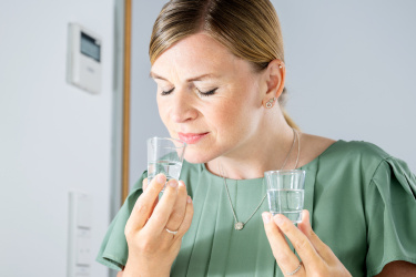 A woman is testing a fluid flavour with her eyes closed.