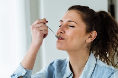 A woman eating a spoonful of natural yoghurt