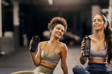Two women in the gym enjoying the fitness break, both laughing. 
