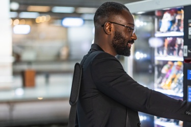 man in front of a vending machine selecting a drink