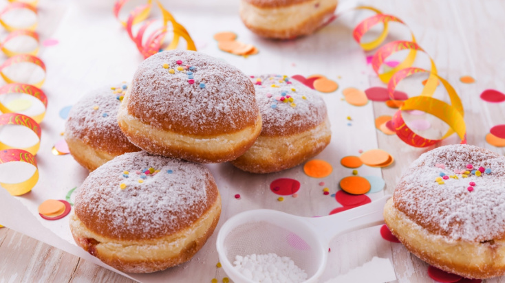 Traditional German "Berliner" - doghnuts without a whole with sugar topping sourrounded by confetti and sprinkles