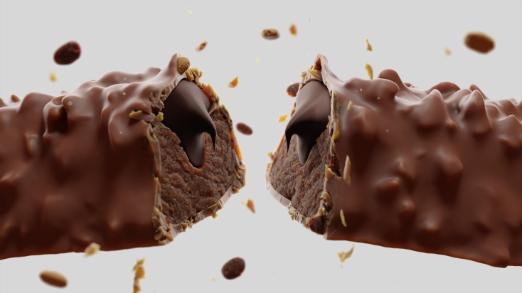 A picture of a delicious double chocolate brownie protein bar breaking in half with chocolate sprinkles "exploding" around it.