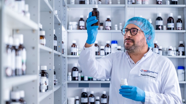 Flavour technologist in flavour lab holding a brown bottle of liquid flavour and reading the label