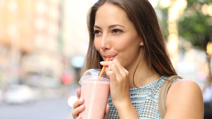 A woman drinking with straw from shake