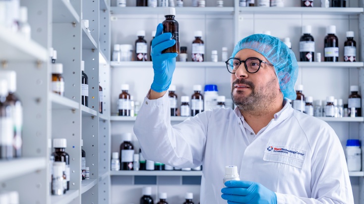 Flavour technologist in flavour lab holding a brown bottle of liquid flavour and reading the label
