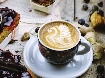 A cup of coffee with blueberry cake on a table in a coffeehouse