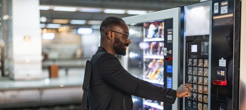 A man selecting drink from a vending machine at the trainstation