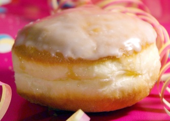 Picture of a jelly-filled doughnut with paper streames on a bright pink background.